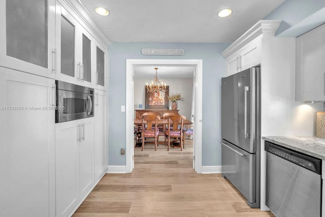 kitchen with light hardwood / wood-style flooring, appliances with stainless steel finishes, a notable chandelier, light stone countertops, and white cabinets