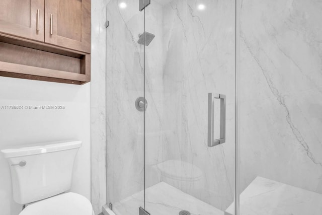 bathroom with a shower with shower door and toilet