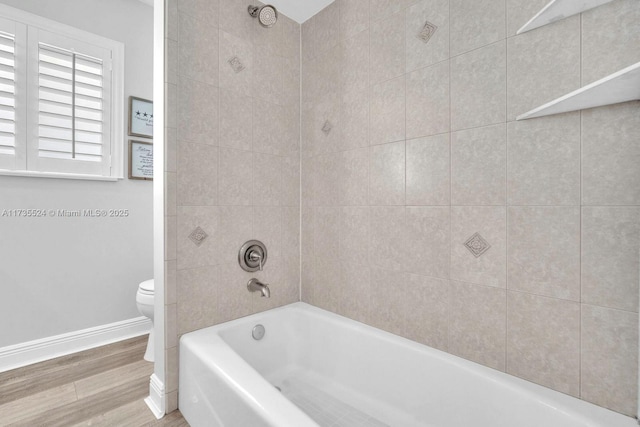 bathroom with tiled shower / bath, wood-type flooring, and toilet