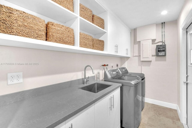 clothes washing area with cabinets, sink, electric panel, and independent washer and dryer