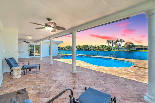 pool at dusk featuring ceiling fan and a patio area