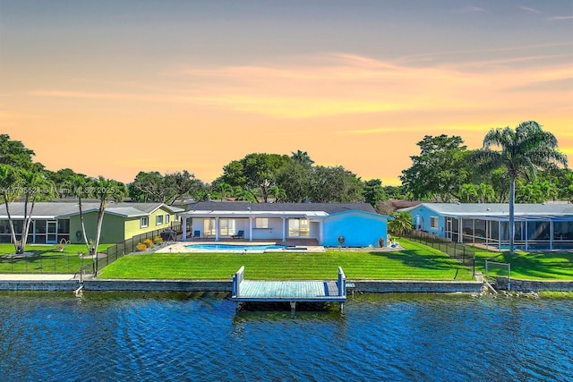 back house at dusk featuring a water view and a yard