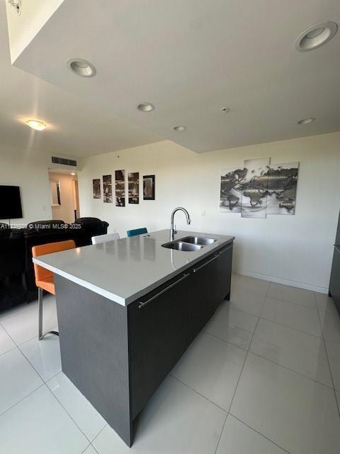 kitchen featuring a kitchen bar, sink, a kitchen island with sink, and light tile patterned floors