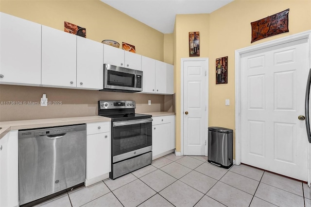 kitchen featuring appliances with stainless steel finishes, light tile patterned floors, and white cabinets