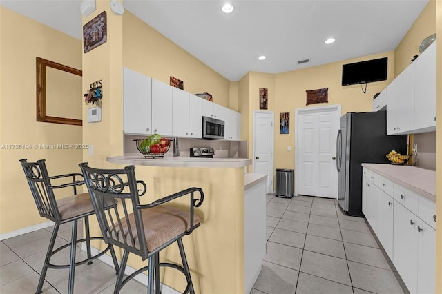 kitchen featuring a breakfast bar area, white cabinets, and appliances with stainless steel finishes