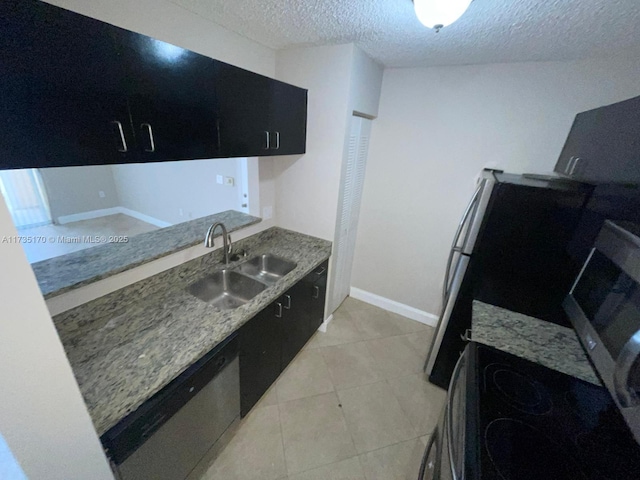 kitchen with light tile patterned flooring, dishwasher, dark cabinetry, and a sink