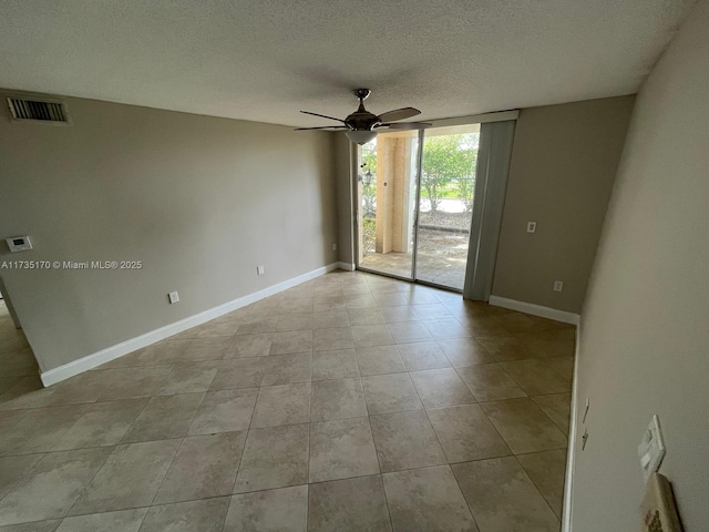 spare room with baseboards, a ceiling fan, visible vents, and a textured ceiling