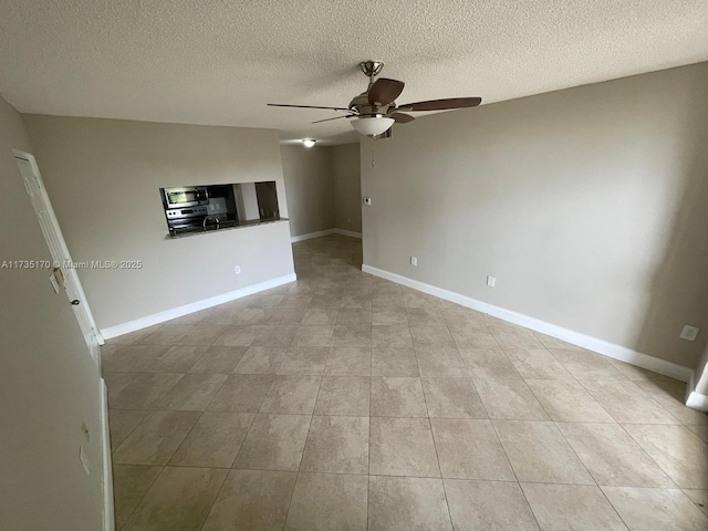 unfurnished living room featuring light tile patterned flooring, a textured ceiling, baseboards, and ceiling fan