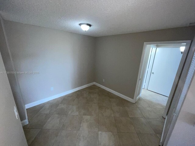 unfurnished bedroom with ceiling fan, a textured ceiling, and light tile patterned floors