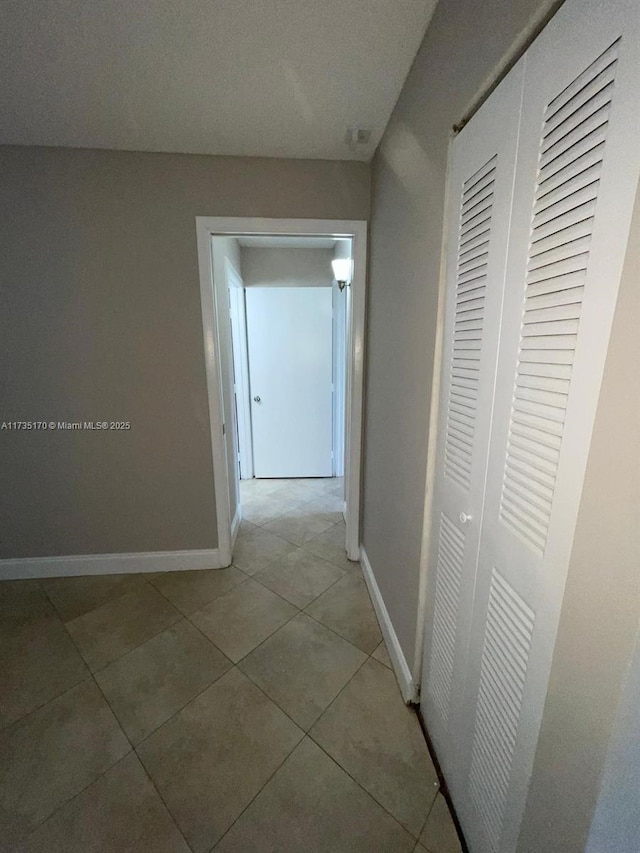 corridor with light tile patterned floors and baseboards