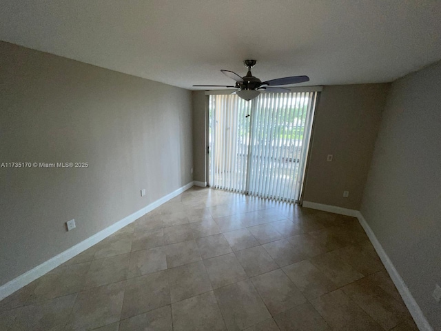 tiled empty room featuring baseboards and ceiling fan