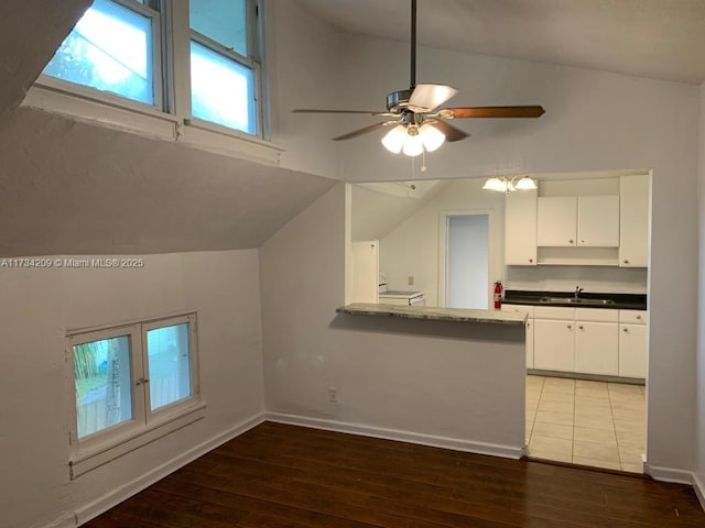 kitchen featuring dark hardwood / wood-style floors, vaulted ceiling, and white cabinets