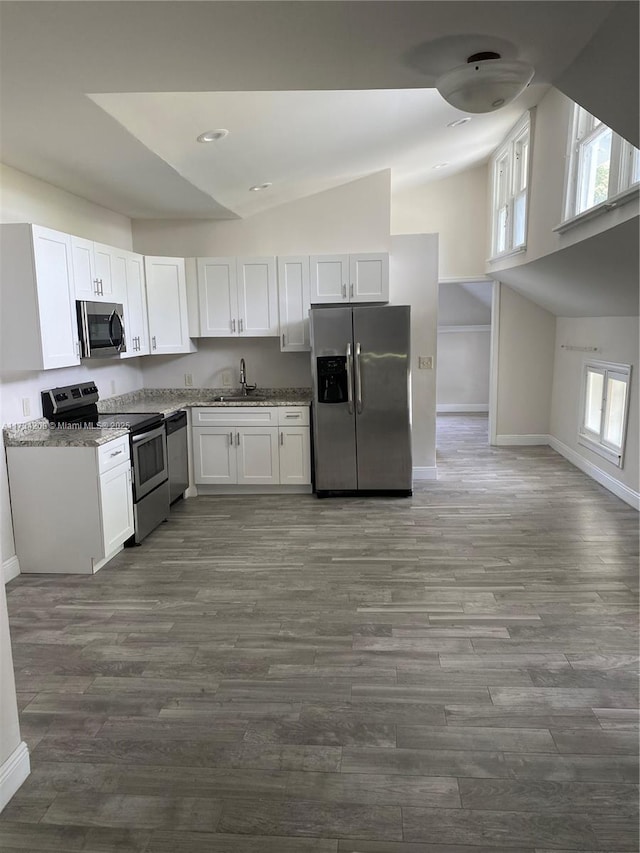 kitchen featuring sink, dark wood-type flooring, stainless steel appliances, light stone countertops, and white cabinets