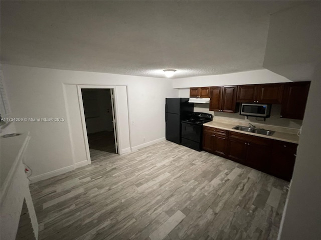 kitchen featuring sink, black appliances, a textured ceiling, and light wood-type flooring