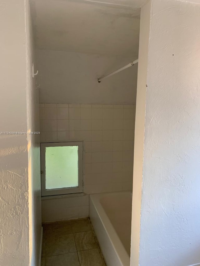 bathroom with tile patterned flooring and a tub