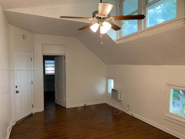 additional living space featuring dark wood-type flooring, ceiling fan, lofted ceiling, and a wall unit AC