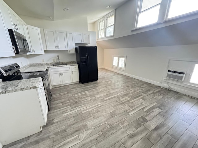 kitchen with appliances with stainless steel finishes, sink, cooling unit, white cabinets, and light hardwood / wood-style floors