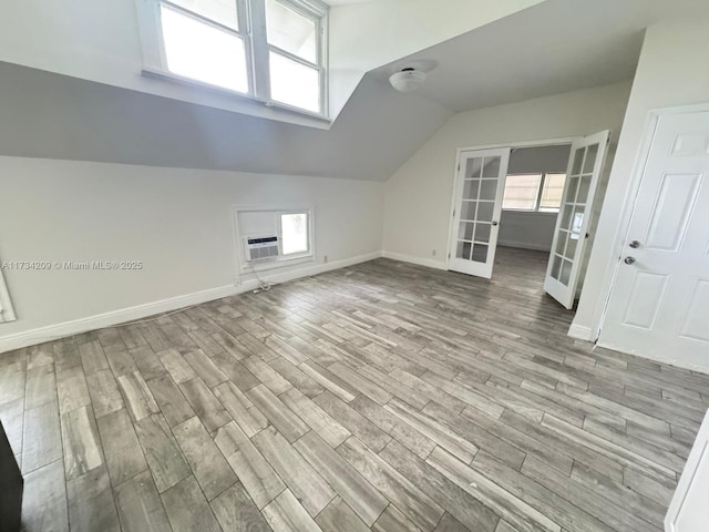 bonus room with french doors, a healthy amount of sunlight, vaulted ceiling, and light wood-type flooring