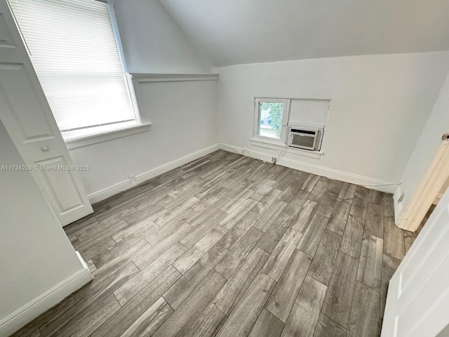 additional living space featuring cooling unit, vaulted ceiling, and light wood-type flooring