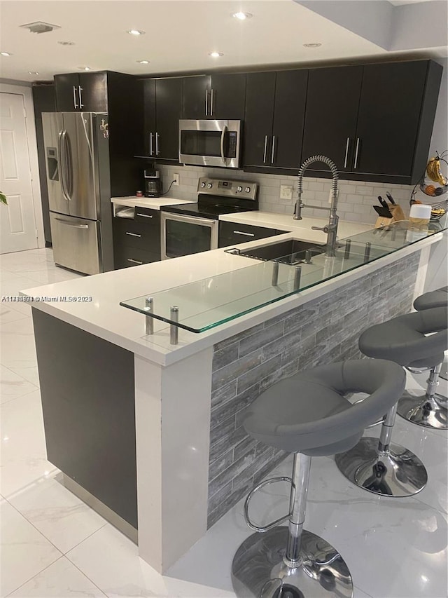 kitchen with appliances with stainless steel finishes, sink, a breakfast bar area, and kitchen peninsula