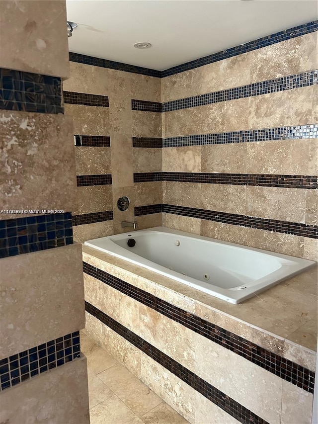 bathroom with tile walls, tiled tub, and tile patterned flooring