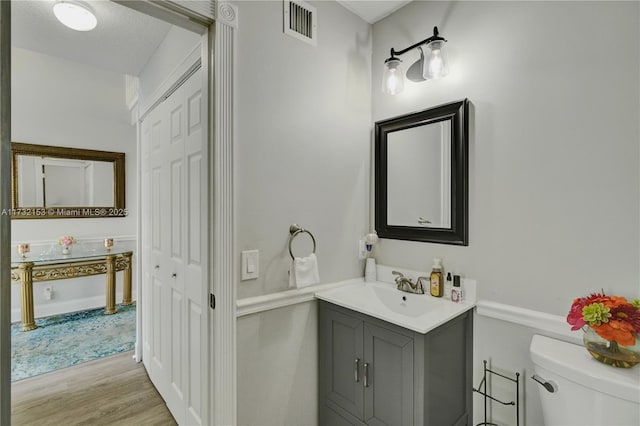 bathroom featuring vanity, toilet, and hardwood / wood-style floors