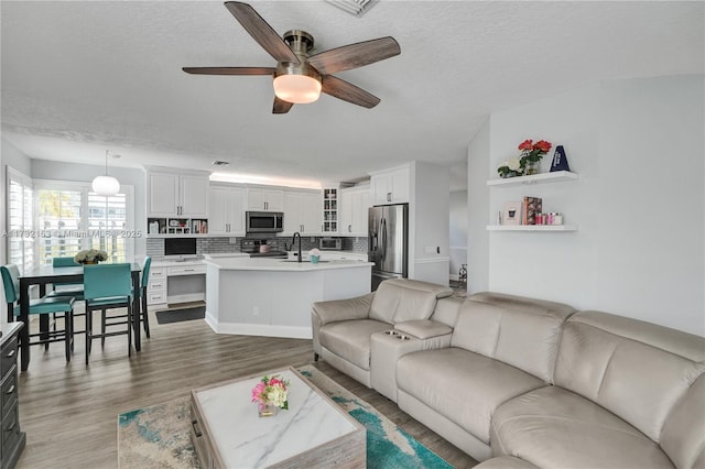 living room featuring a textured ceiling, wood-type flooring, and ceiling fan