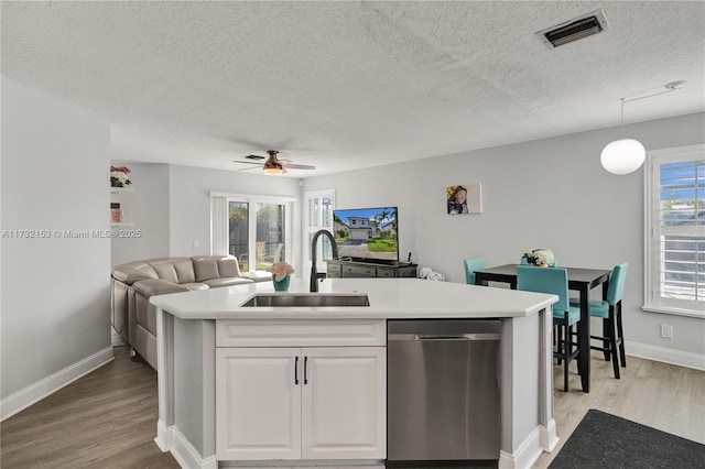 kitchen with decorative light fixtures, white cabinetry, sink, stainless steel dishwasher, and plenty of natural light