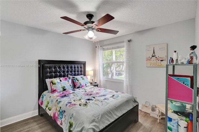 bedroom featuring dark hardwood / wood-style flooring, ceiling fan, and a textured ceiling