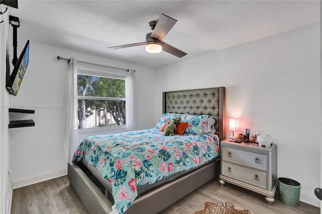 bedroom featuring hardwood / wood-style flooring, ceiling fan, and a textured ceiling