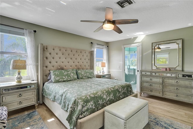 bedroom featuring multiple windows, ensuite bath, and light wood-type flooring