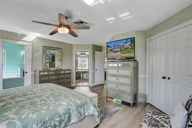 bedroom featuring ensuite bath, ceiling fan, a textured ceiling, a closet, and light wood-type flooring