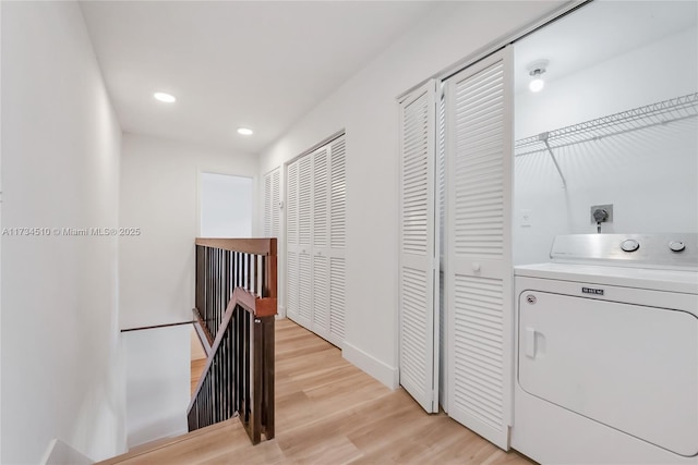 hall with washer / dryer and light hardwood / wood-style flooring