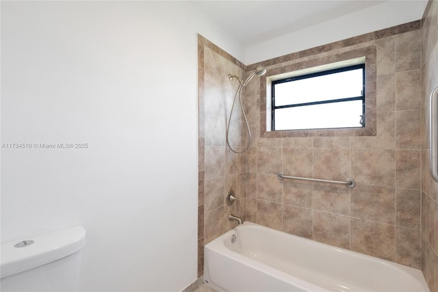 bathroom with tiled shower / bath combo and toilet