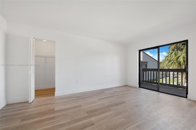 interior space featuring a walk in closet, light hardwood / wood-style flooring, and access to outside