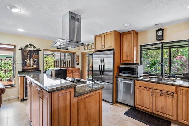 kitchen featuring stainless steel appliances, a center island, island range hood, and dark stone counters