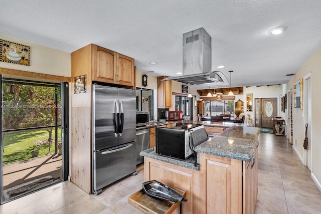 kitchen with island range hood, a textured ceiling, dark stone countertops, hanging light fixtures, and appliances with stainless steel finishes