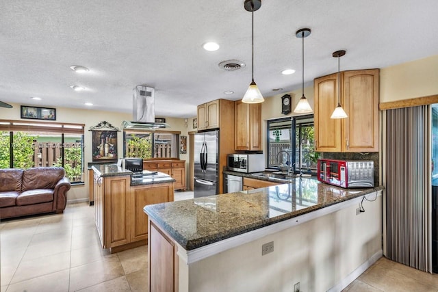 kitchen featuring dark stone countertops, appliances with stainless steel finishes, kitchen peninsula, a kitchen island, and pendant lighting