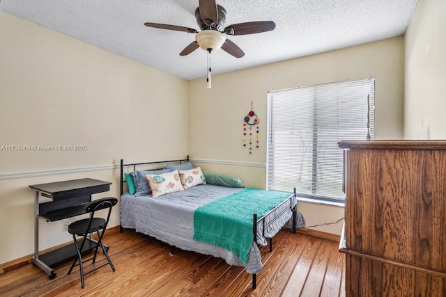 bedroom featuring ceiling fan, light hardwood / wood-style floors, and a textured ceiling