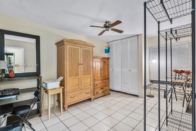 interior space with light tile patterned floors, a textured ceiling, and ceiling fan