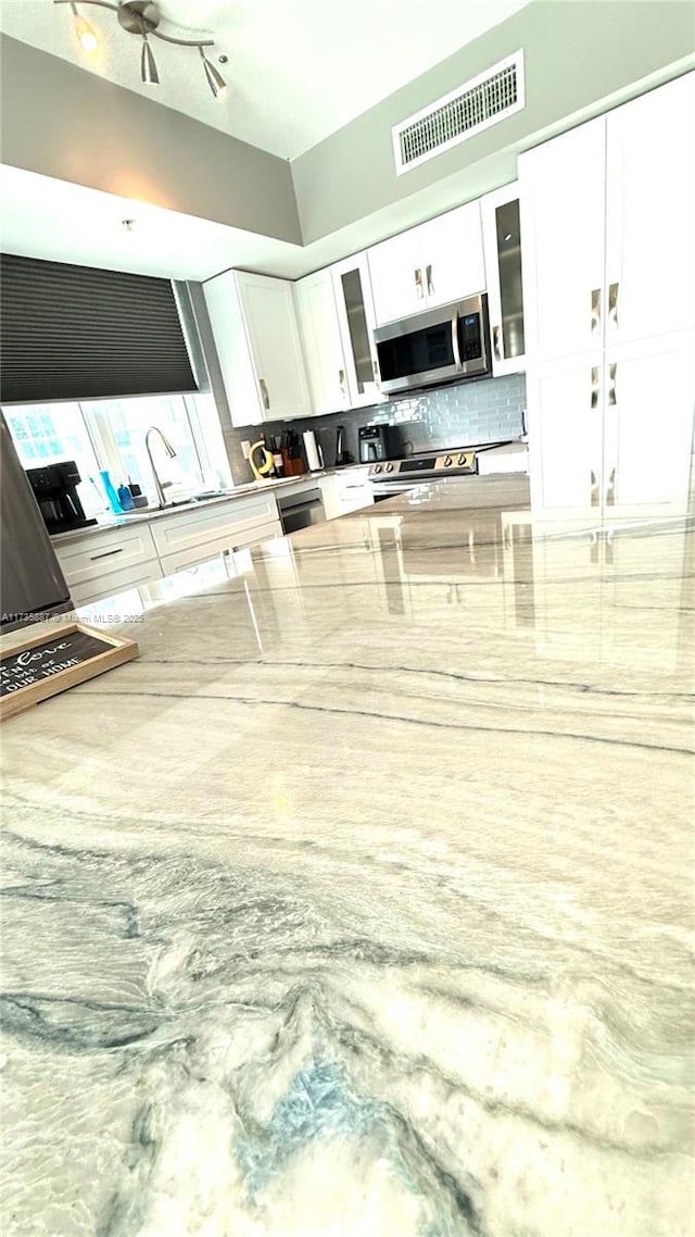 kitchen featuring tasteful backsplash, white cabinets, and appliances with stainless steel finishes