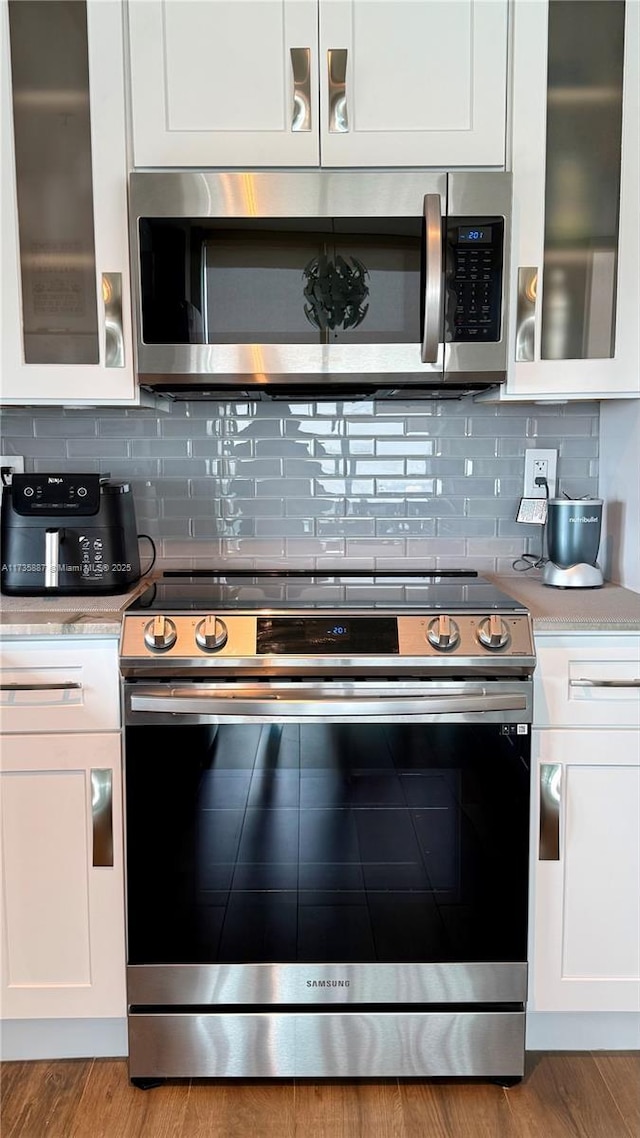 kitchen featuring tasteful backsplash, appliances with stainless steel finishes, light wood-type flooring, and white cabinets