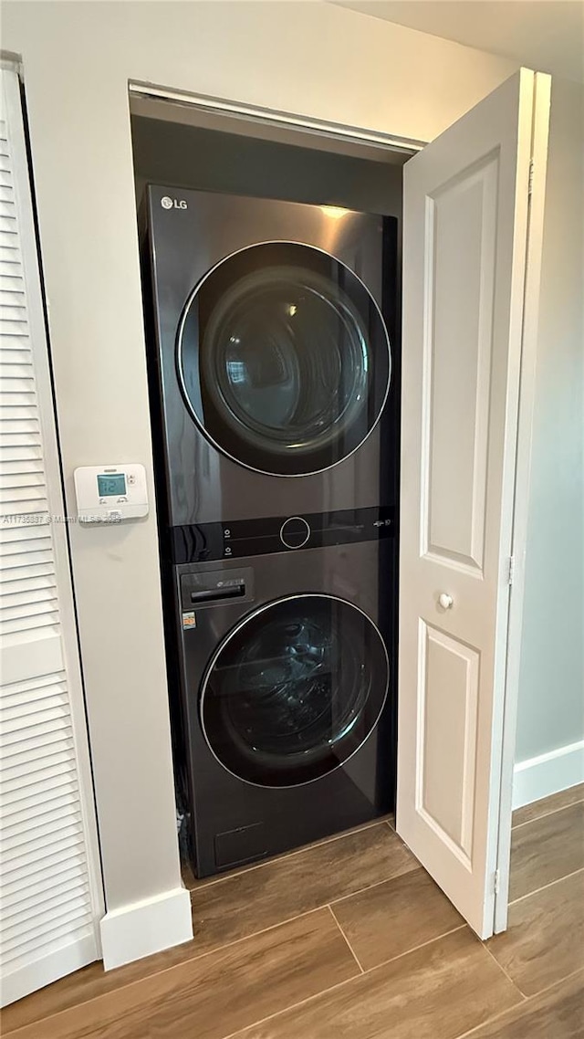 clothes washing area with stacked washing maching and dryer and hardwood / wood-style floors