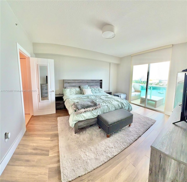 bedroom featuring access to outside, a textured ceiling, and light wood-type flooring