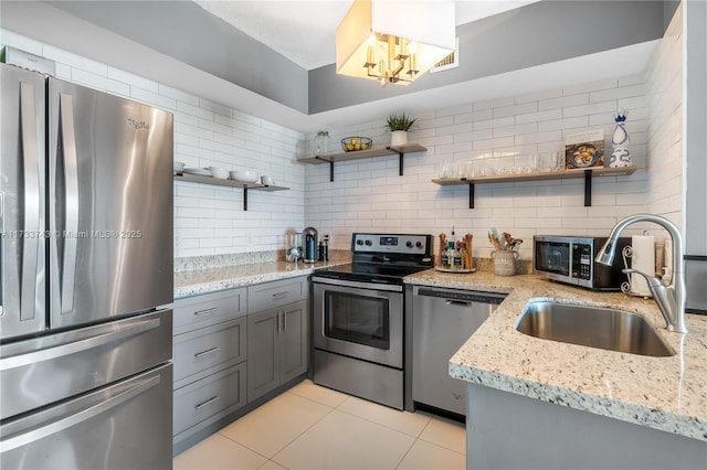 kitchen with appliances with stainless steel finishes, tasteful backsplash, sink, light tile patterned floors, and light stone counters