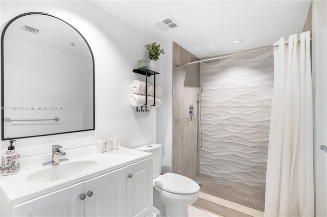 bathroom featuring vanity, tiled shower, and toilet