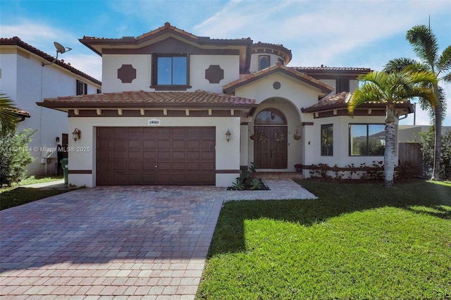 mediterranean / spanish house with a front lawn, decorative driveway, an attached garage, and stucco siding