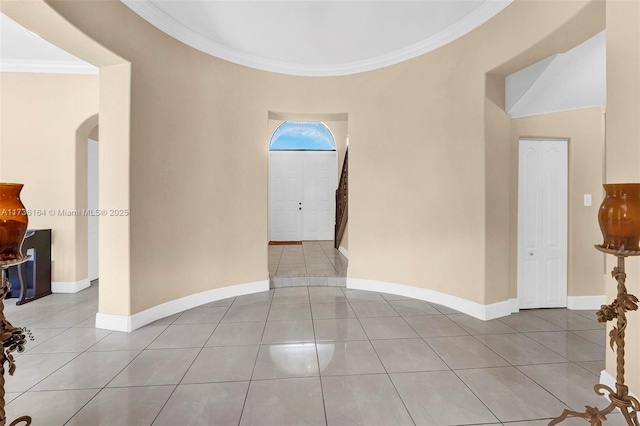 unfurnished room featuring light tile patterned floors, baseboards, arched walkways, and crown molding