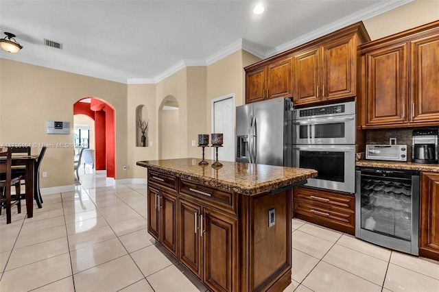 kitchen featuring light tile patterned flooring, beverage cooler, visible vents, appliances with stainless steel finishes, and crown molding