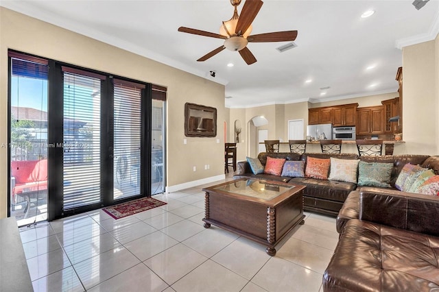 living area with light tile patterned floors, visible vents, arched walkways, baseboards, and ornamental molding